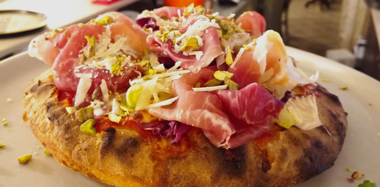 Pizza alla pala with ham, salad leaves and cheese shavings