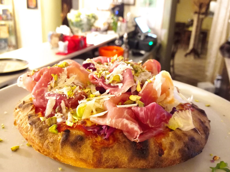 Pizza alla pala con prosciutto, insalata e scaglie di formaggio